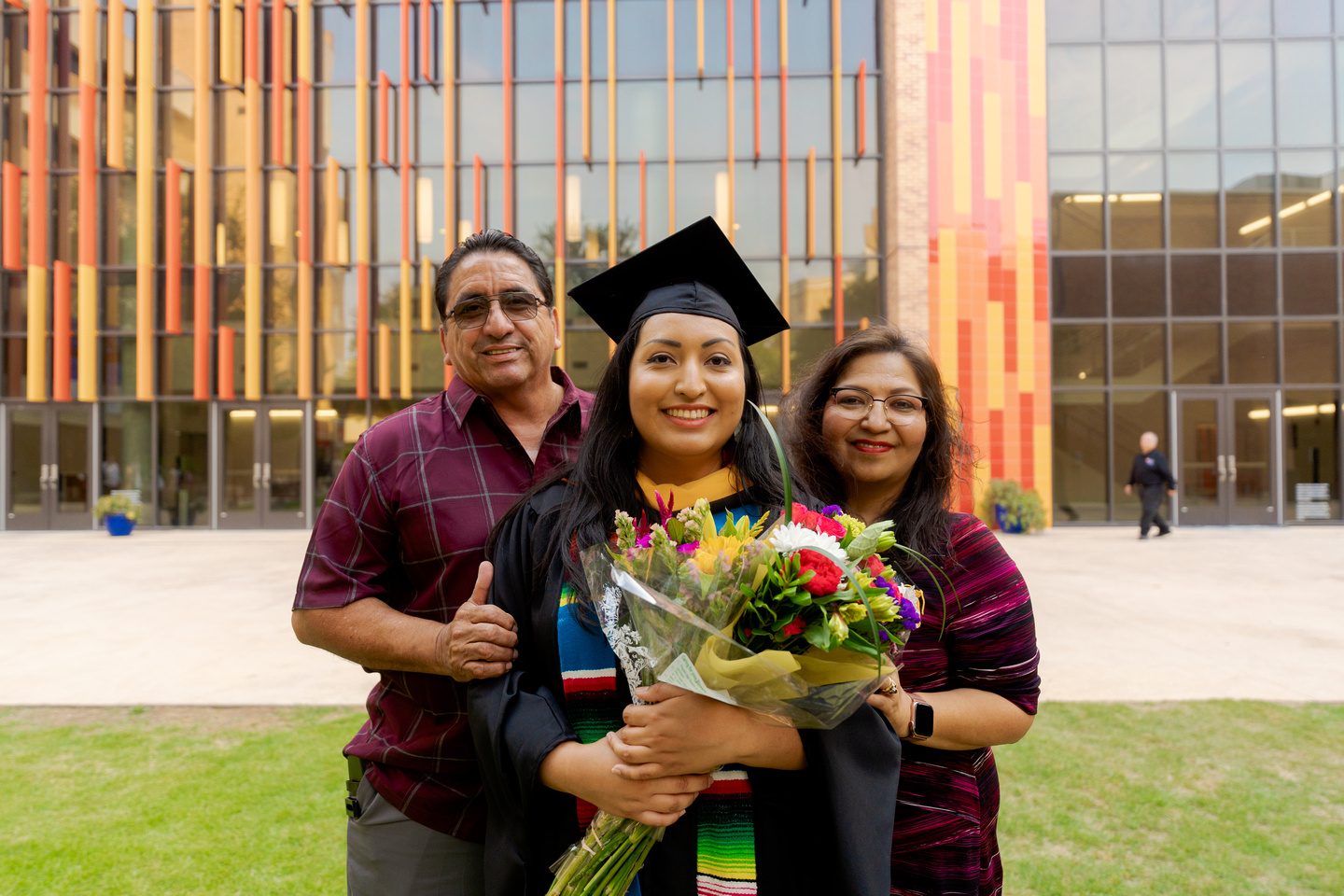 Graduating student with her parents and flowers