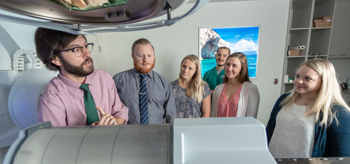 A group of people standing behind a large medical imaging device.