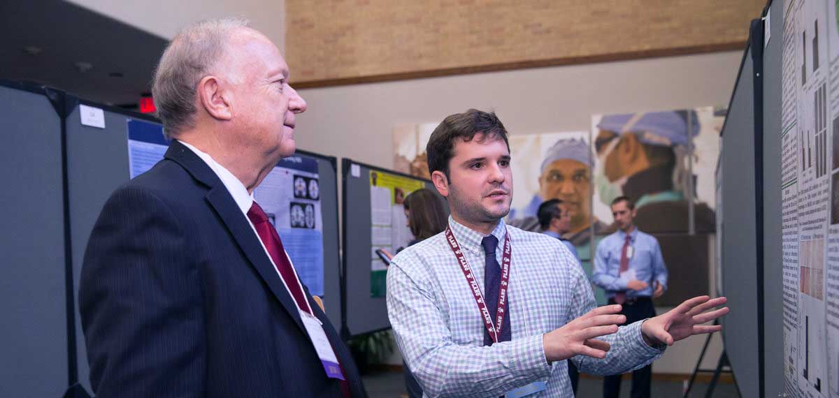 Biomedical Engineering Ph.D. student explaining his educational poster to an exhibitor judge