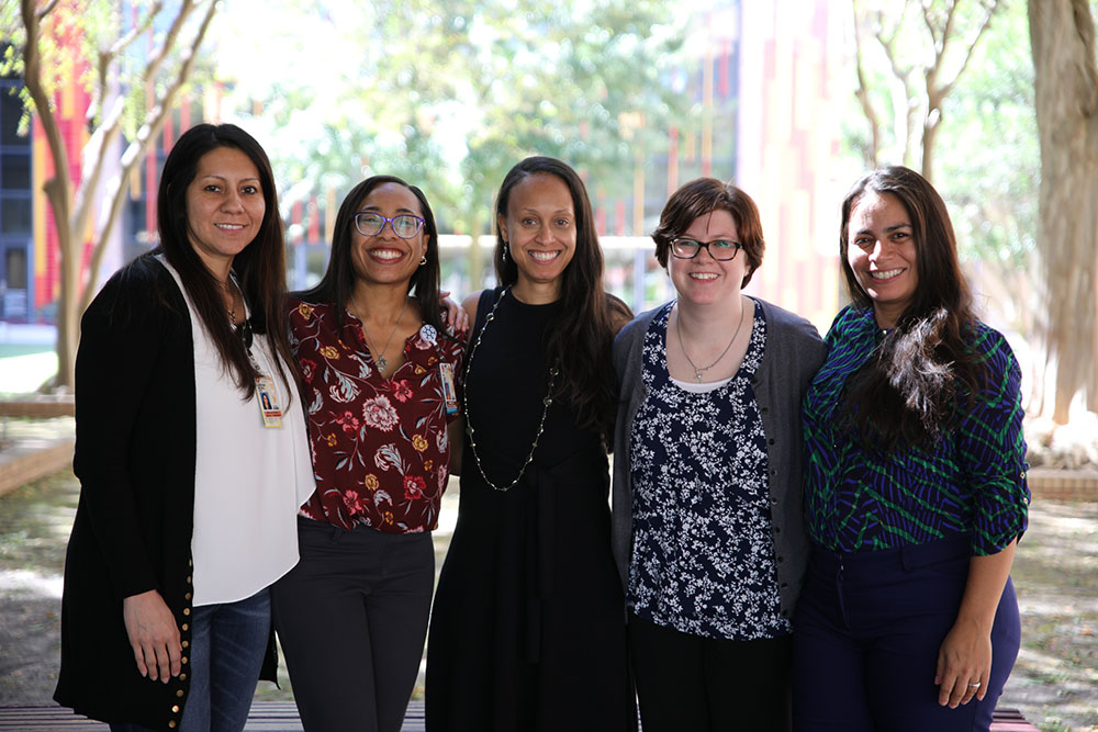 A group of Nursing PhD students smiling in the courtyard on campus