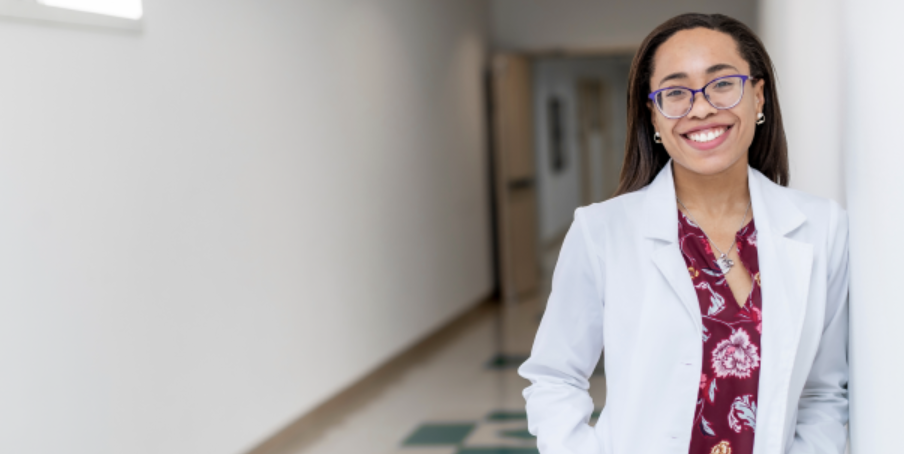 Nursing student in white coat smiling