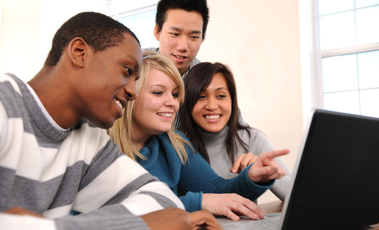 group of students gathered around a laptop