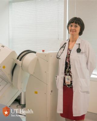 Dr. Agoston in her white coat standing in front of medical equipment.
