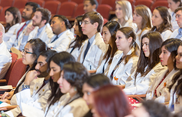 clinical students wearing white coats in an auditorium