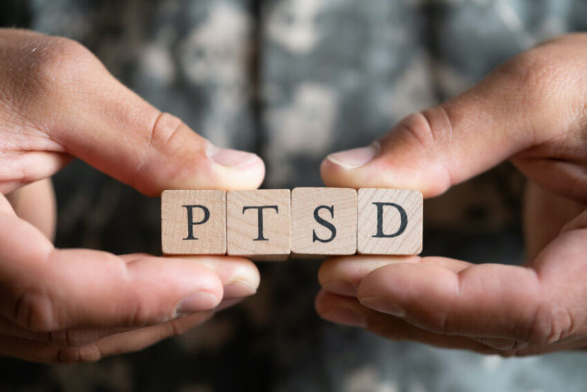 hands holding wooden blocks with the letters PTSD on them