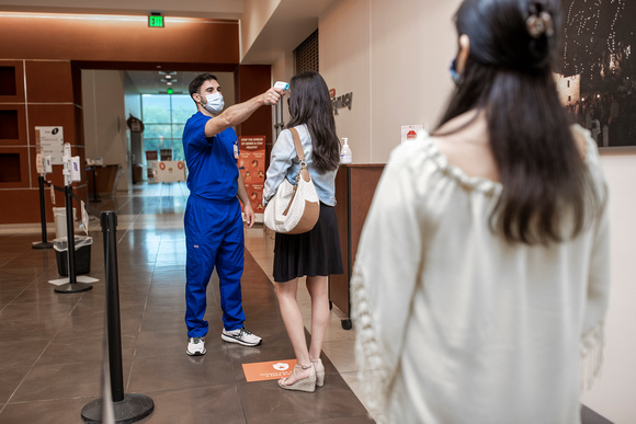 UT Health staff member conducts temperature check on a visitor