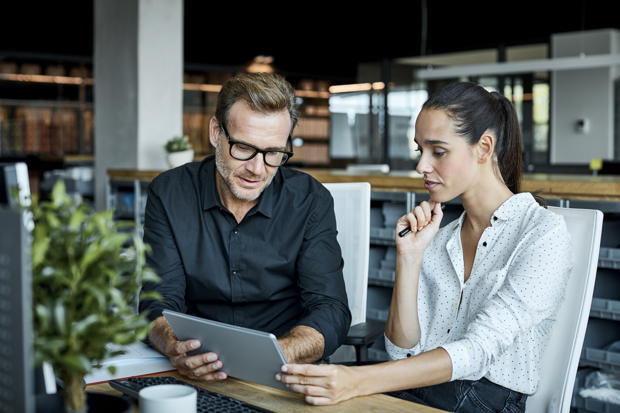 Professional male and female colleagues looking at tablet