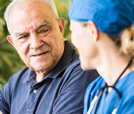 Older male patient talking to female surgeon