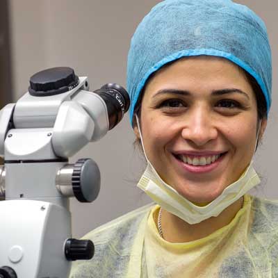 Comprehensive dentistry specialist in surgical scrubs with microscope.