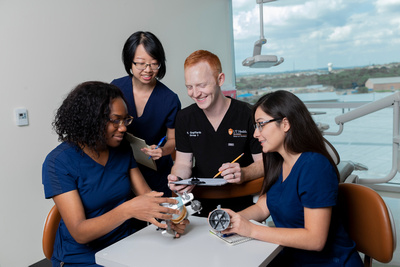 students gathered around table looking at dental mold