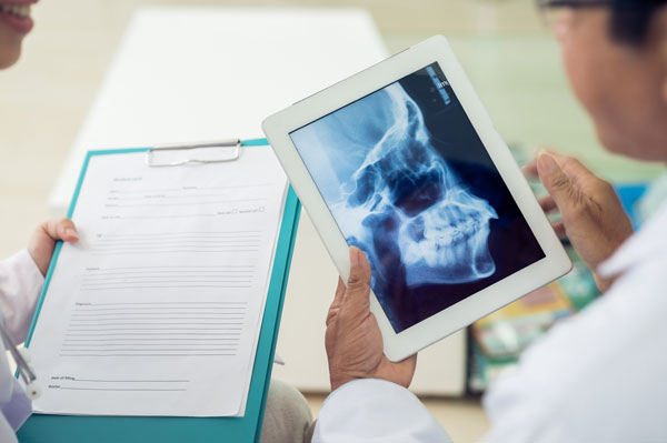 Oral and maxillofacial surgeon reviewing a patient's facial x-rays