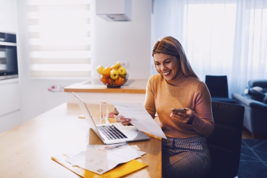 Woman on computer with paperwork and phone