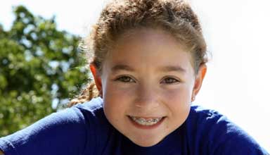 Happy dental patient with traditional braces and orthodontics 