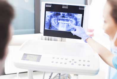 Dentist showing a patient dental x-rays and explaining how oral infection can lead to further difficulties 