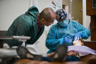 Dentist working on child as father looks on